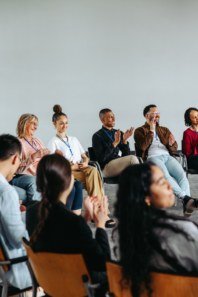 A diverse group of people clapping and celebrating together during an Excellence Seminars session
