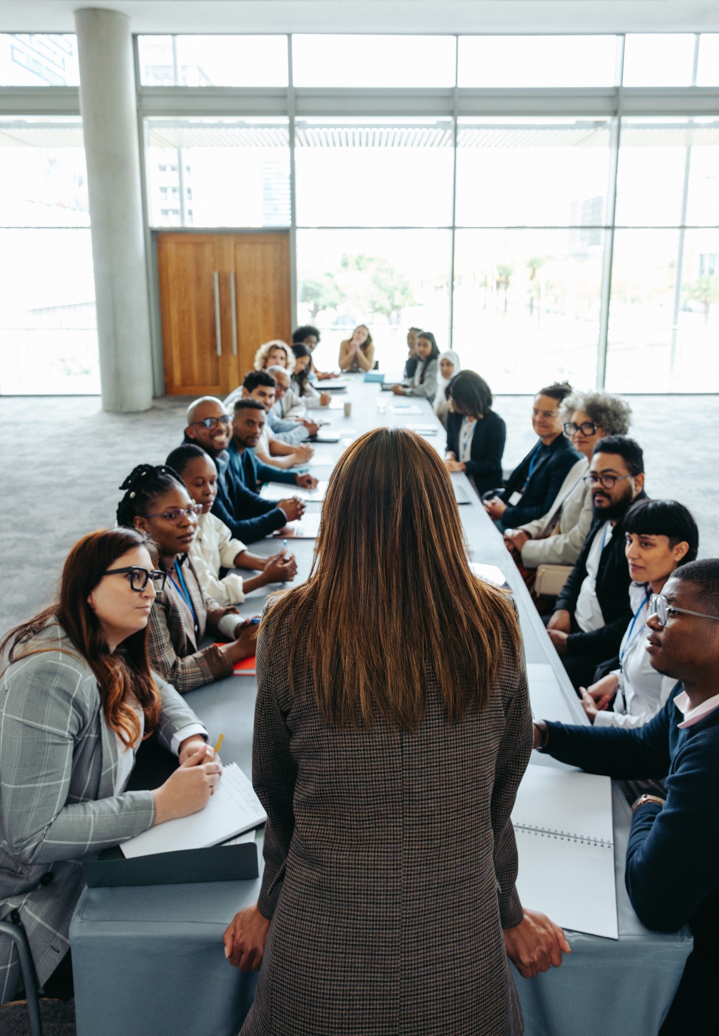 An empowered woman leader addressing a diverse group of colleagues in a professional meeting held in a contemporary office environment